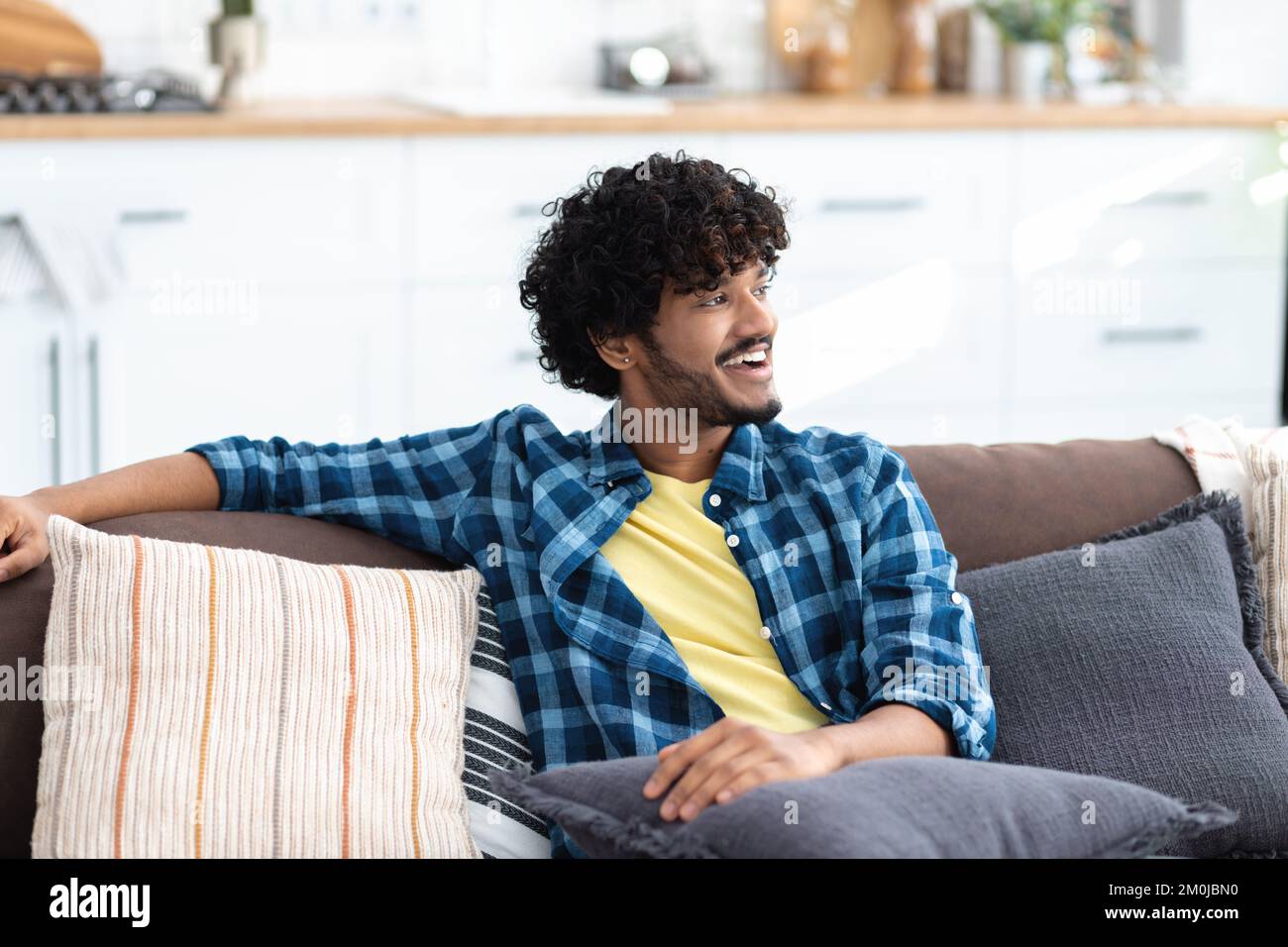 man relaxing, dreaming about something sitting at home on a comfortable sofa. Man enjoying lazy leisure time Stock Photo