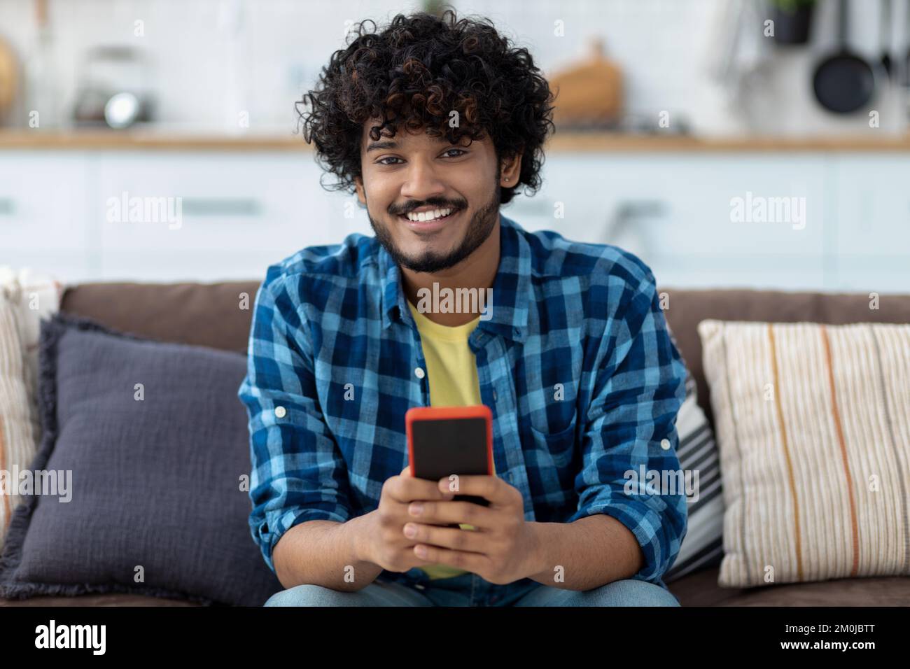 Asian man using mobile phone, chatting online sitting Indian male holding smartphone Stock Photo
