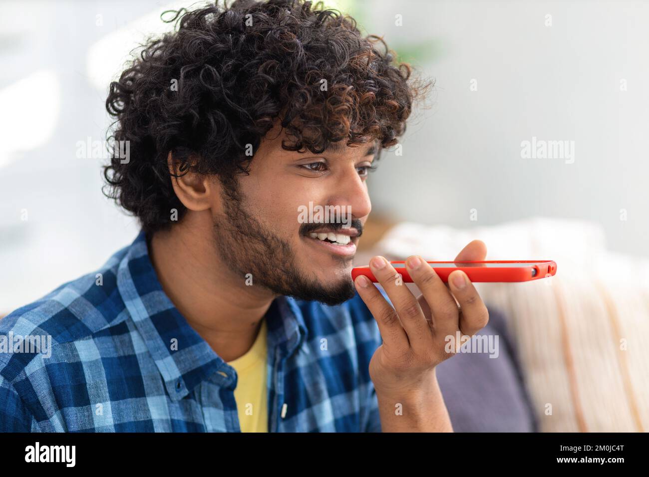 young Asian man sending voice message through using mobile phone close-up, smiling friendly Stock Photo