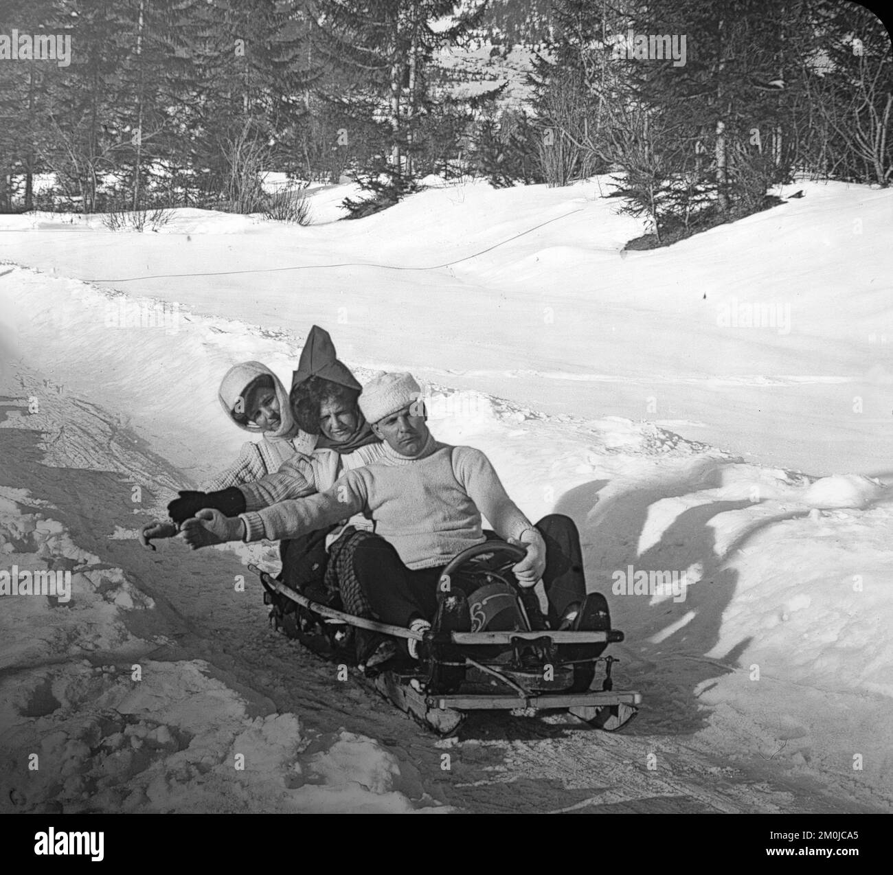 Early 20th century vintage photograph taken in the French Alps, showing three people on a toboggan, or an early type of Bob-Sleigh. Stock Photo