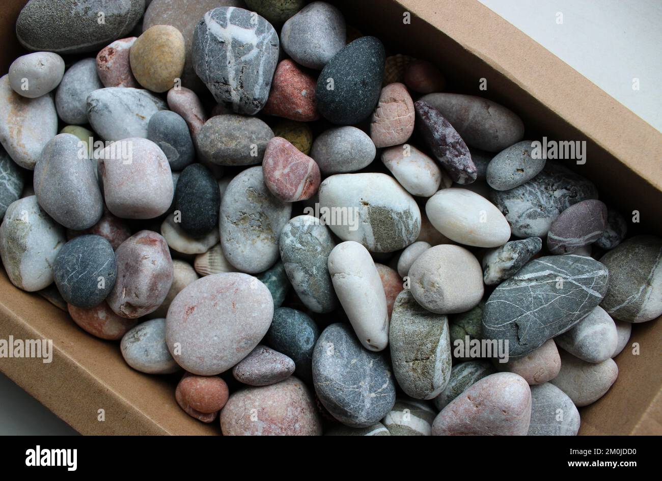 Multi Colored Pebbles With Streaks In Kraft Paper Box Concept For Background Stock Photo