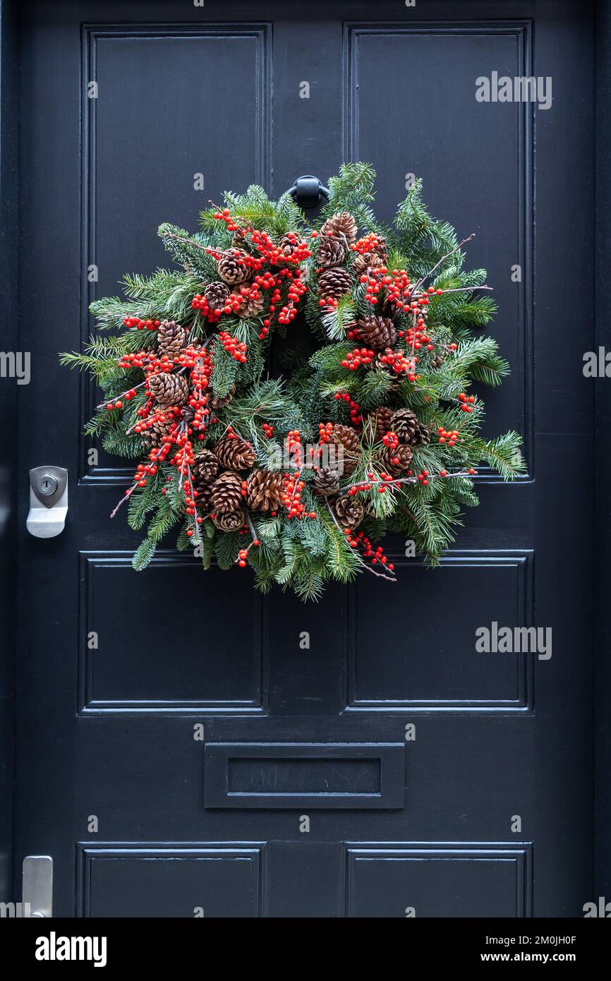 a wreath of fir branches adorned with red hypericum berries and pine ...