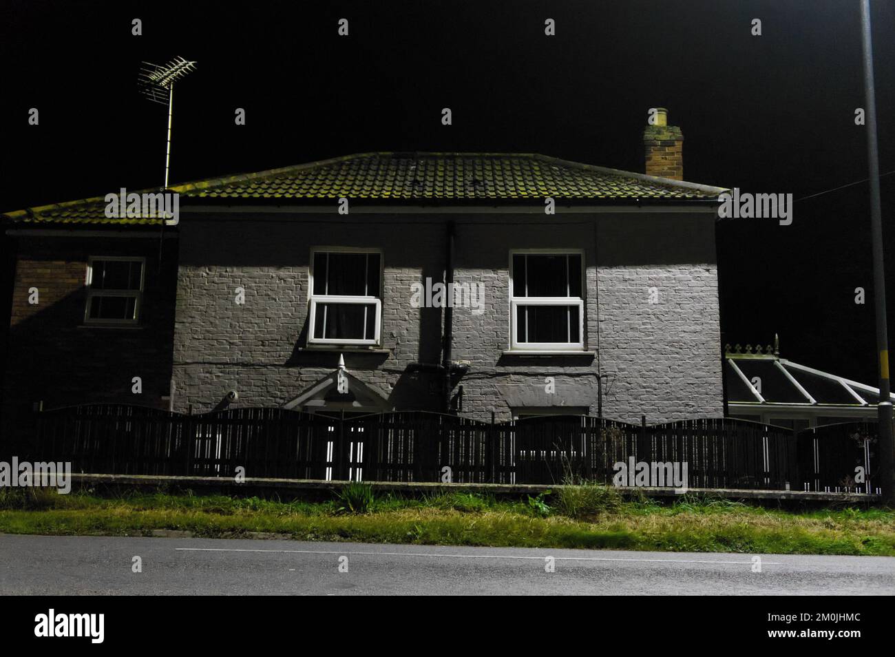 Old house with a picket fence lit-up by street lighting at night Stock Photo