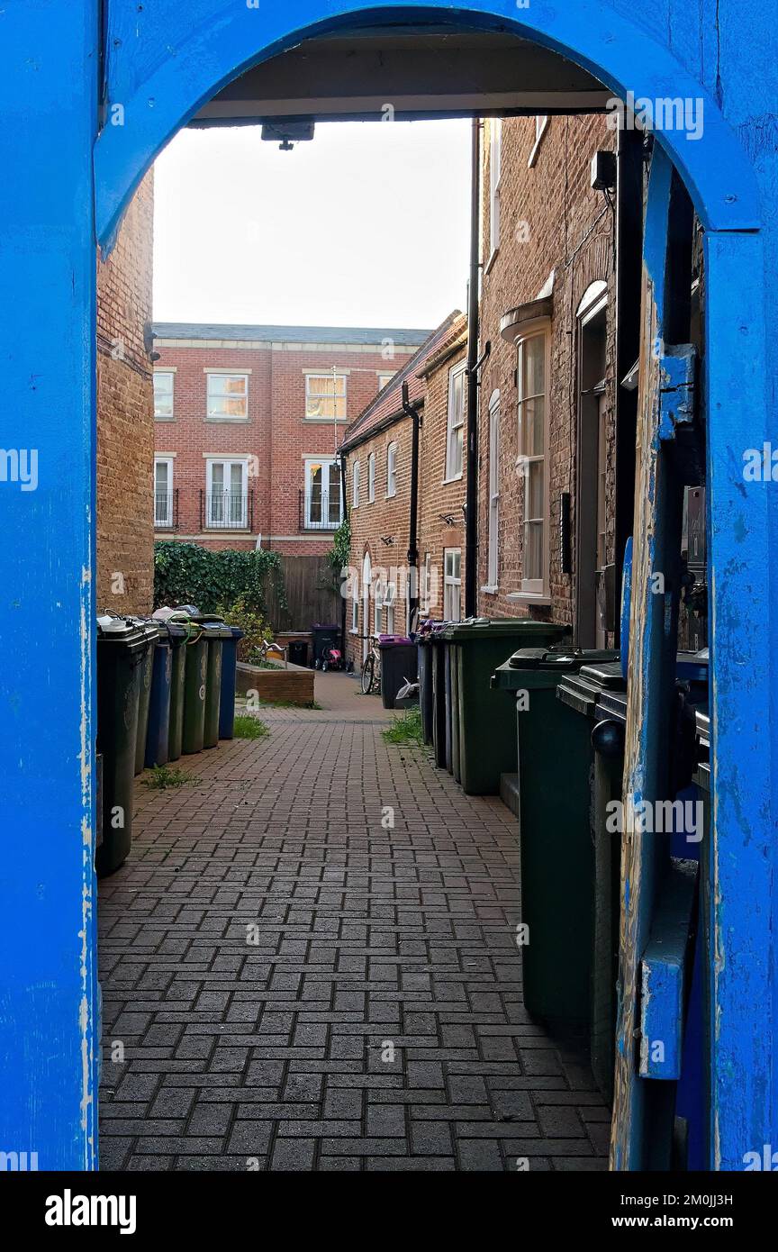 The backyard of a modern apartment block is viewed through a blue door archway Stock Photo