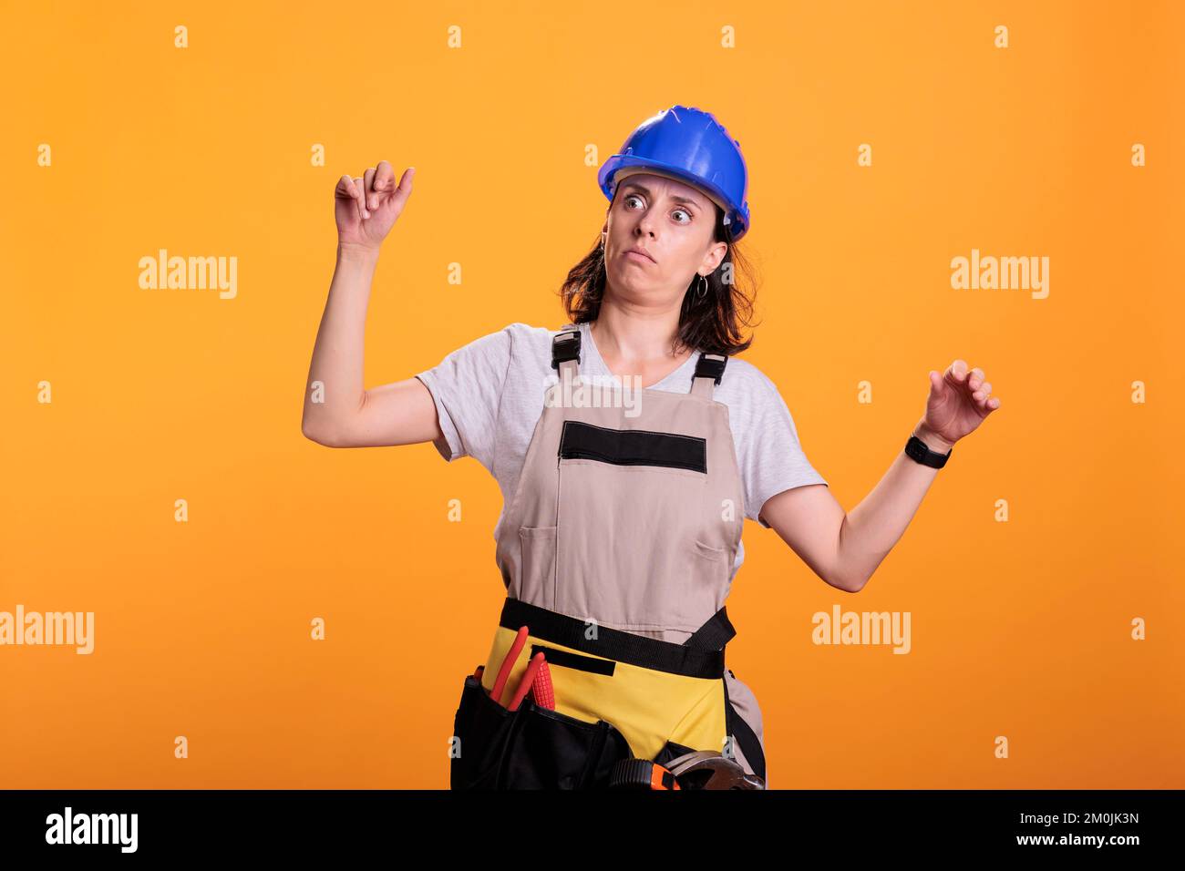 Woman engineering constructor acting dizzy and tired, standing over yellow background and losing balance. Young contractor builder experiencing dizziness and being thoughtful, studio shot. Stock Photo