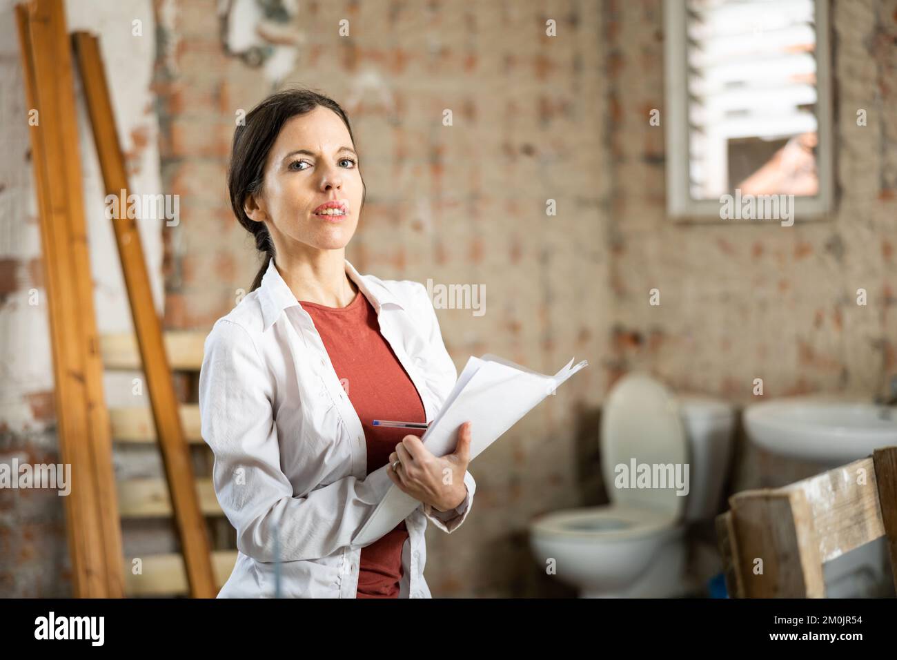 Interested brunette making notes while planning home renovation Stock Photo
