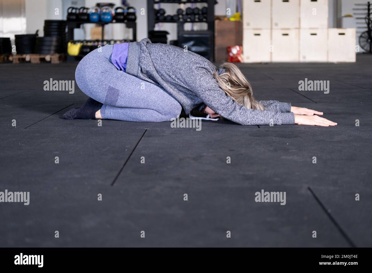 Side view of a blond mid adult woman resting in child's pose during her ...