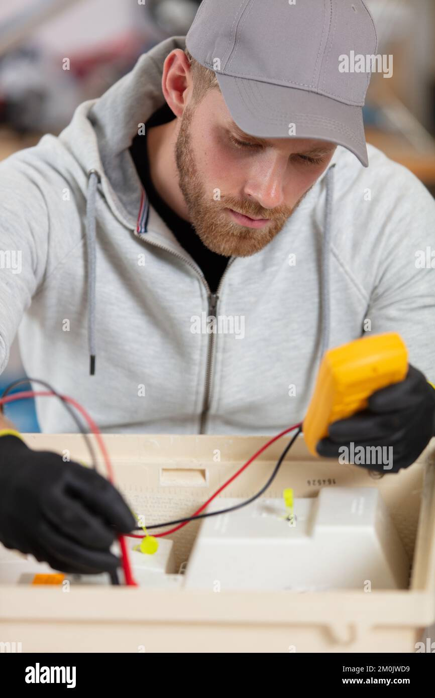 technician checking broken device at table in repair shop Stock Photo