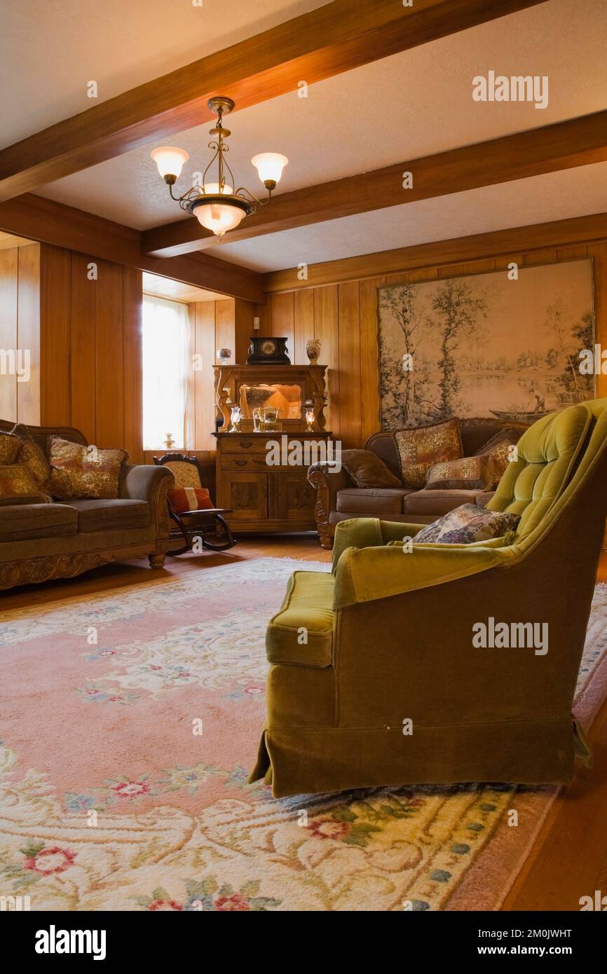 Green upholstered armchair, brown sofas and antique dresser in living room inside old circa 1834
