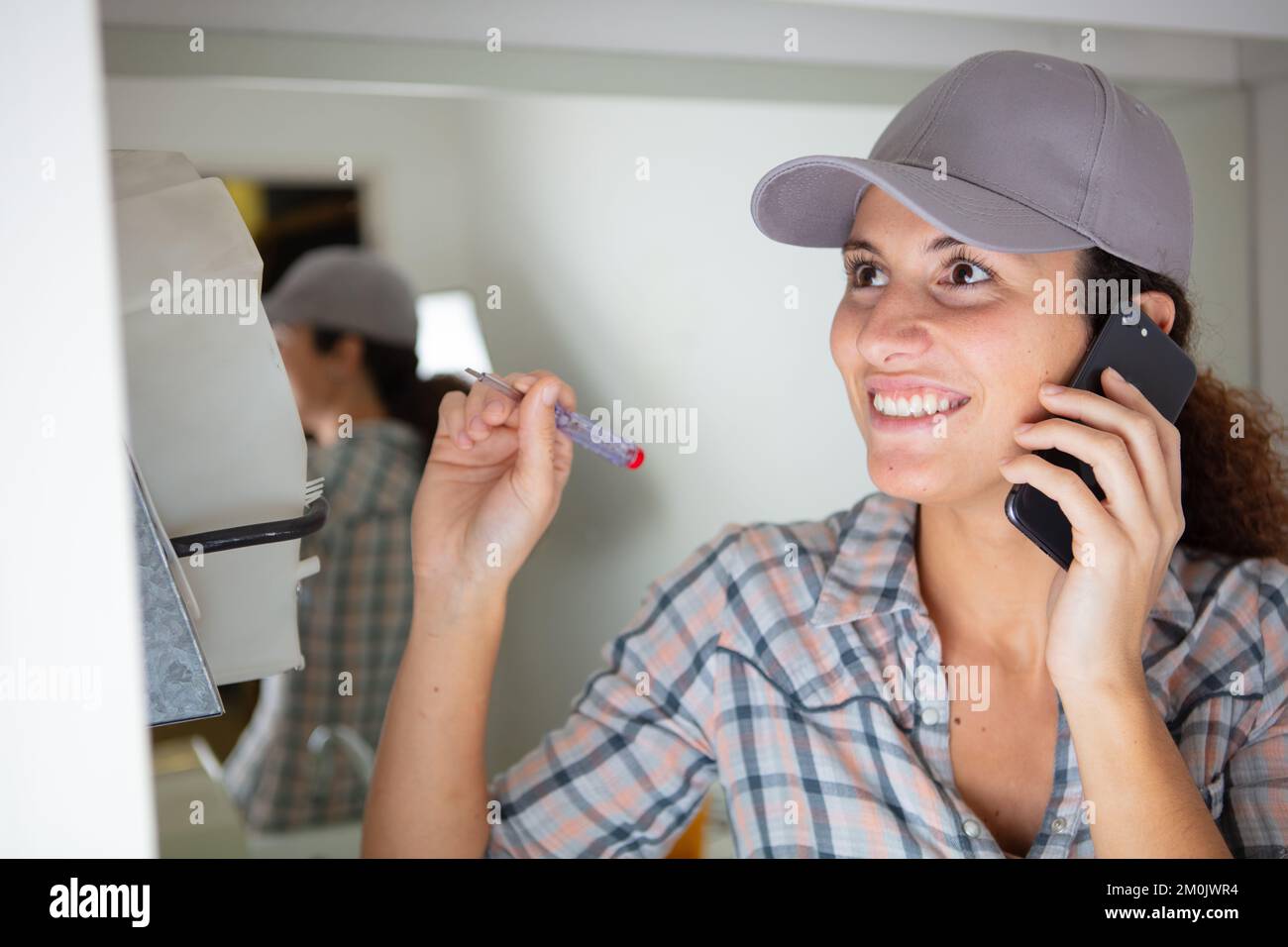 happy female builder with screwdriver talking on smartphone Stock Photo