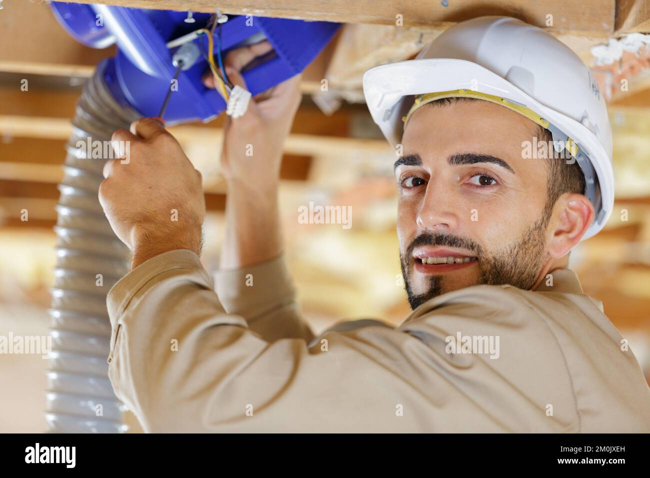 builder examines ventilation in the ceiling Stock Photo