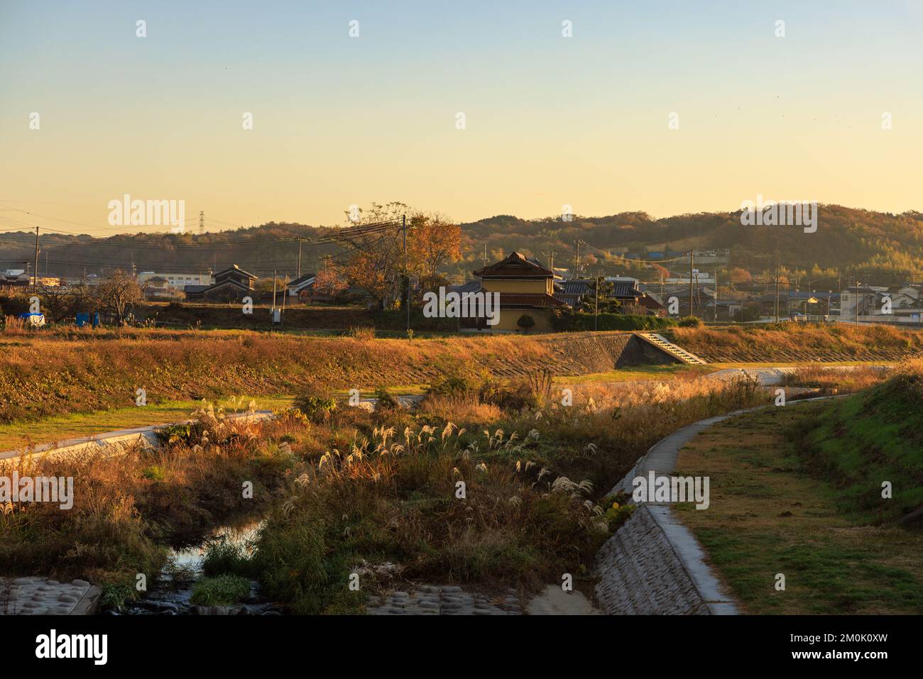 Early morning golden light on river bend through small Japanese town Stock Photo