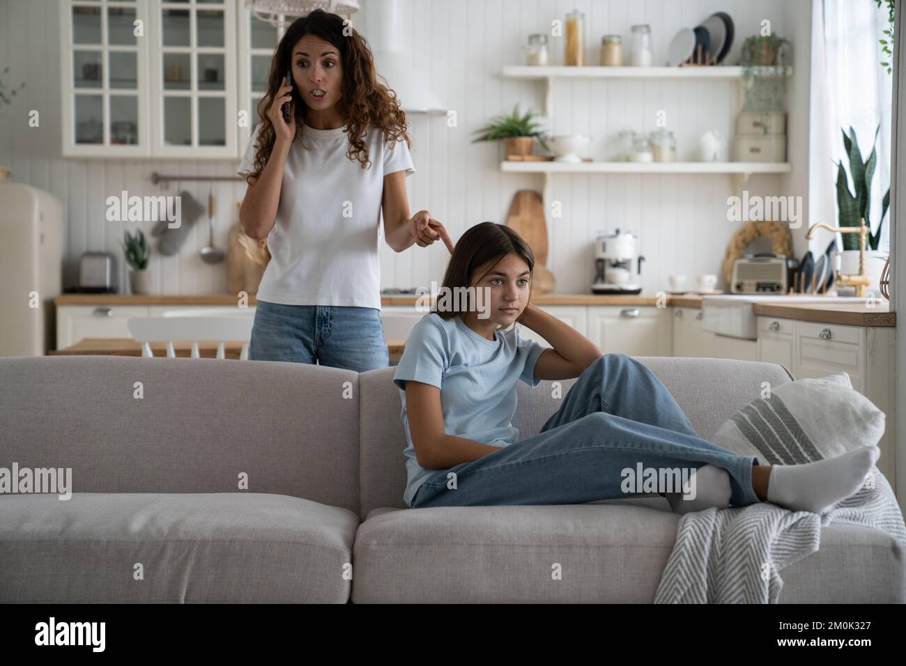 Dissatisfied woman arguing with daughter tutor on phone after end of school year with bad grades Stock Photo
