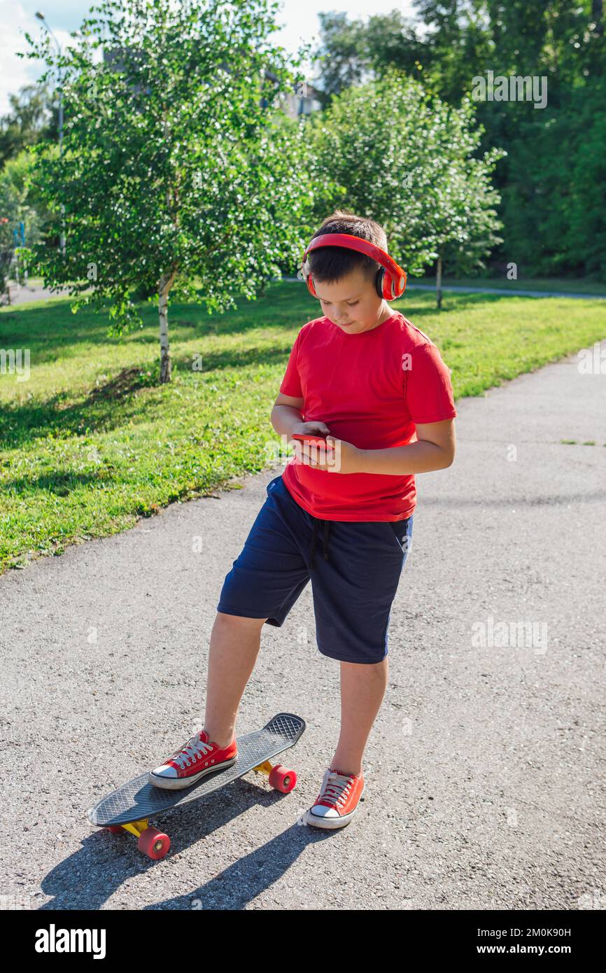 Chubby ten years old boy spends free time training skating in the city park. Boy looking on