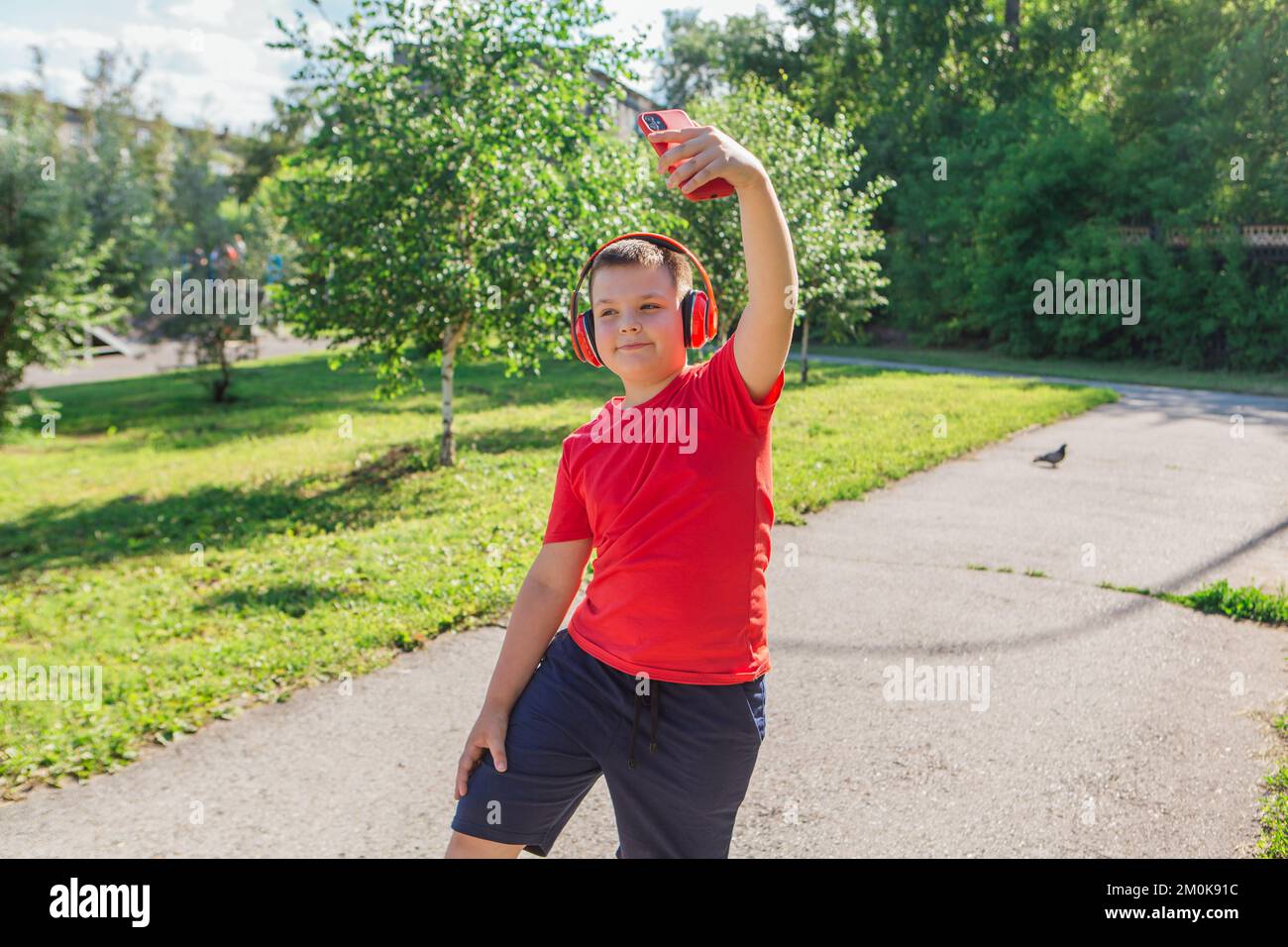 Happy chubby ten years old boy with headphones outdoors. Boy taking
