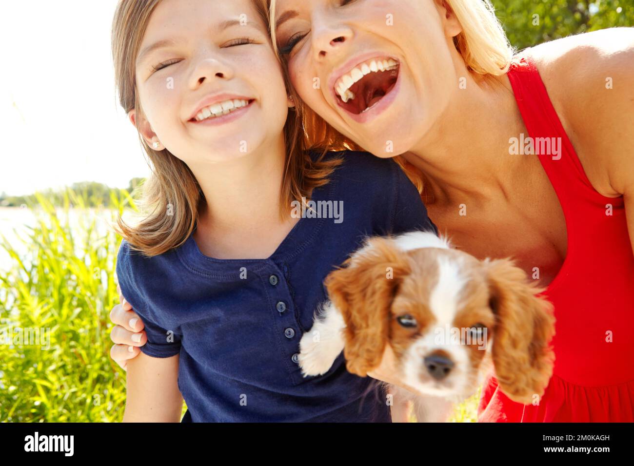 Quality time with mom and the puppy. A happy mother and daughter holding a cute puppy while they stand outside. Stock Photo