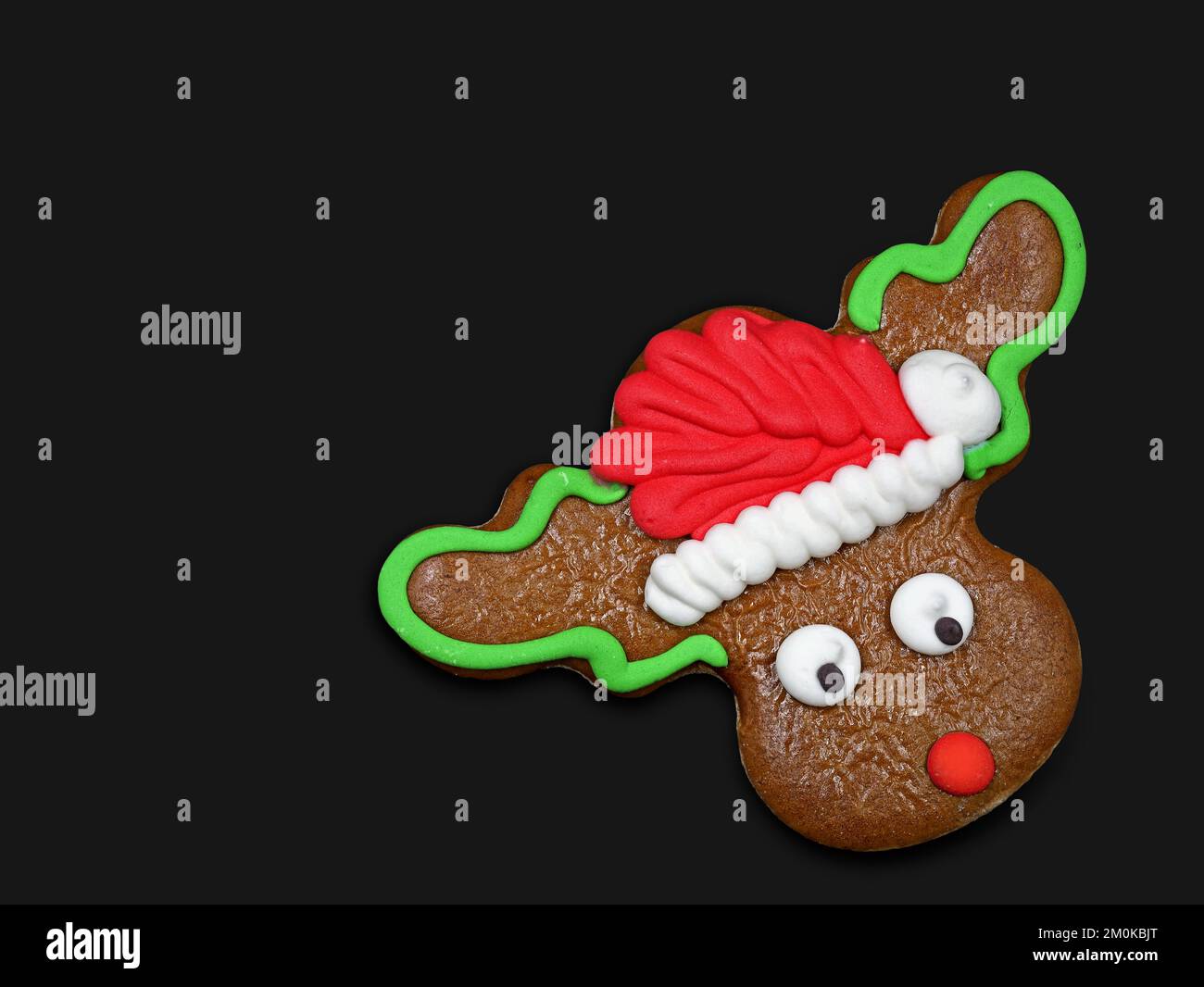 Christmas reindeer cookie, rudolph with santa hat gingerbread isolated on black background with copy space Stock Photo