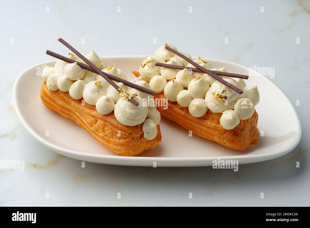 Two eclairs with white custard on whhite plate Stock Photo