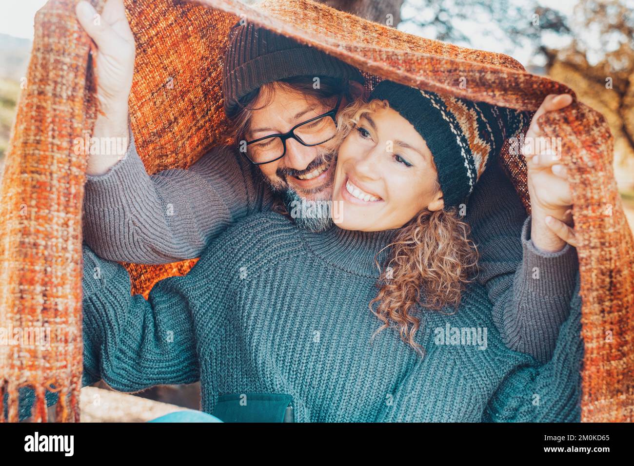 Young mature happy couple enjoy leisure activity together under a colorful cover in outdoor. Friendship and relationship people man and woman having f Stock Photo