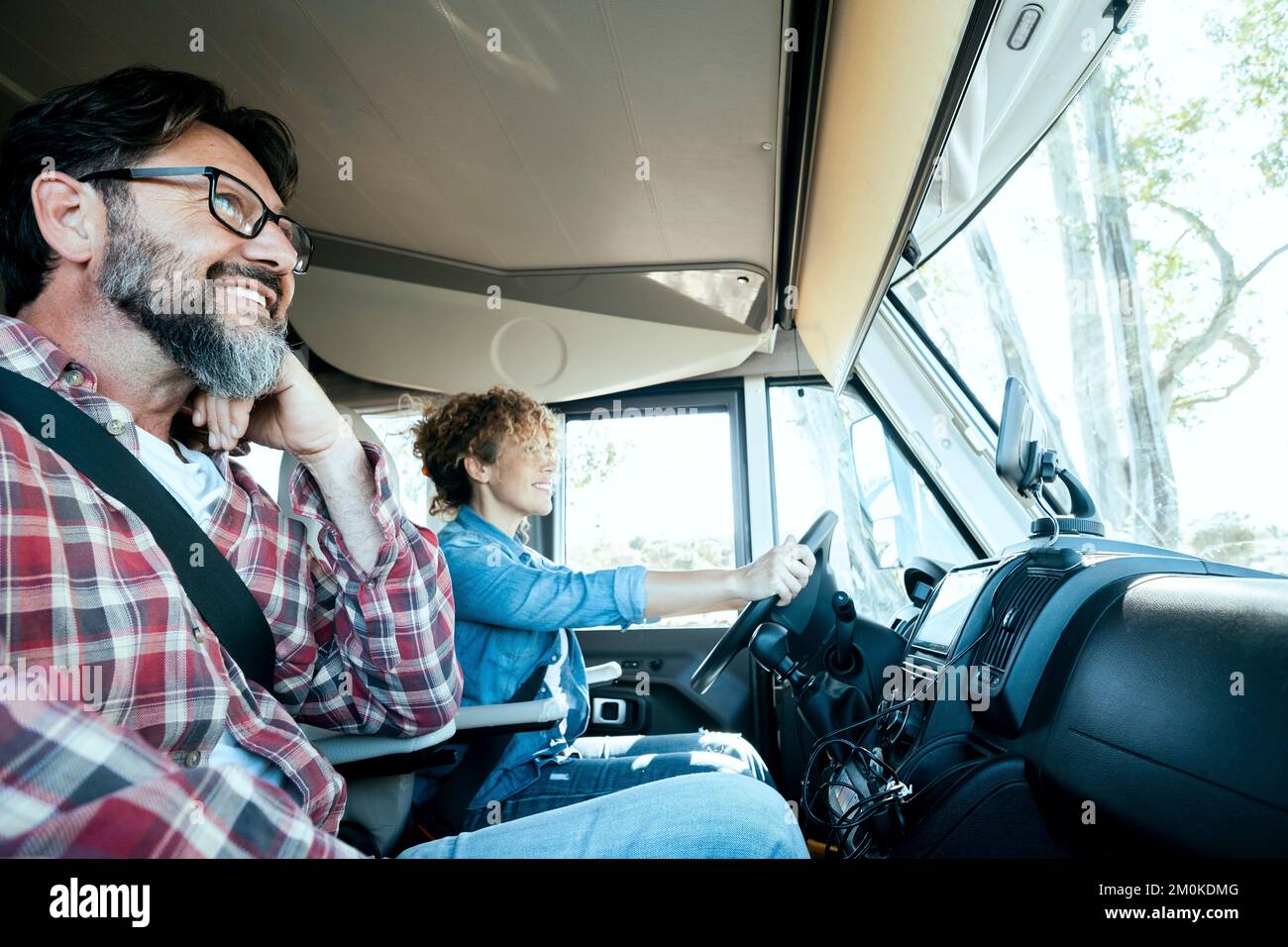 Woman driver driving a camper van with happy man on passenger seat. Alternative couple enjoying travel and van motorhome holiday vacation and lifestyl Stock Photo