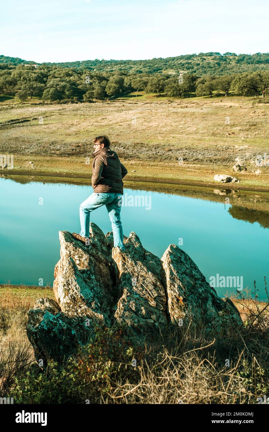 One standing man enjoy wild landscape with river and country side woods forest. Concept of adventure and explore. Male people enjoy journey explore ac Stock Photo