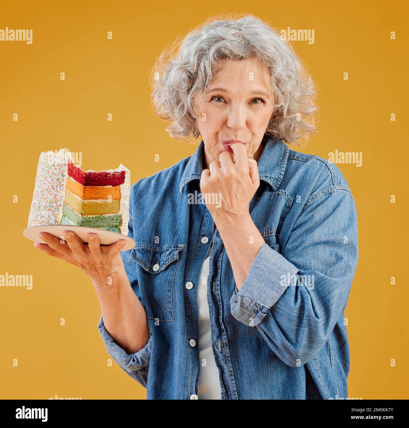 One happy mature caucasian woman holding a colourful cake with a slice ...