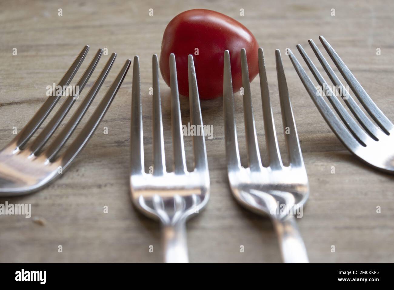 ripe pachino tomato and four metal forks Stock Photo