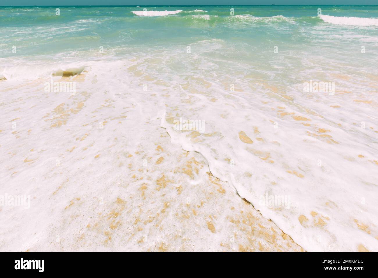 Ocean water foam splashes washing sandy beach. Amazing landscape scenery. Crashing waves of sandy coastline. Sea ocean water surface with small waves Stock Photo