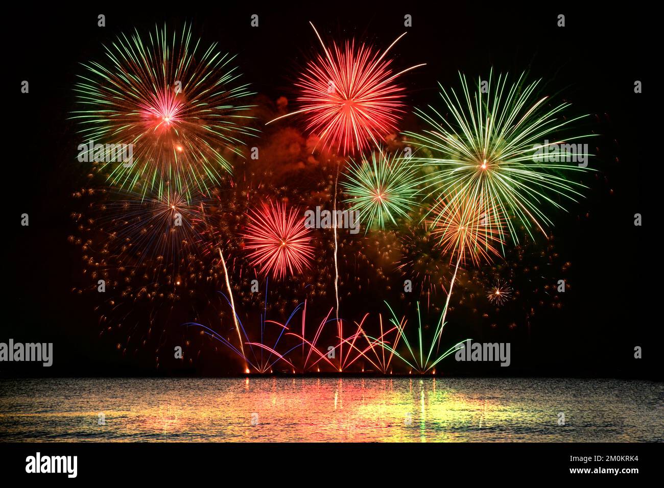 Colorful fireworks celebration from the sea with the midnight sky background. Stock Photo