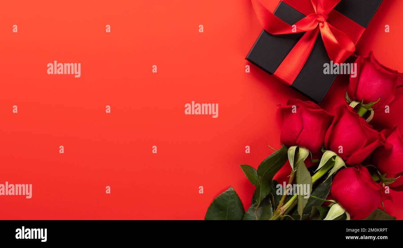 Valentines day card with gift box and rose flowers. On red background ...