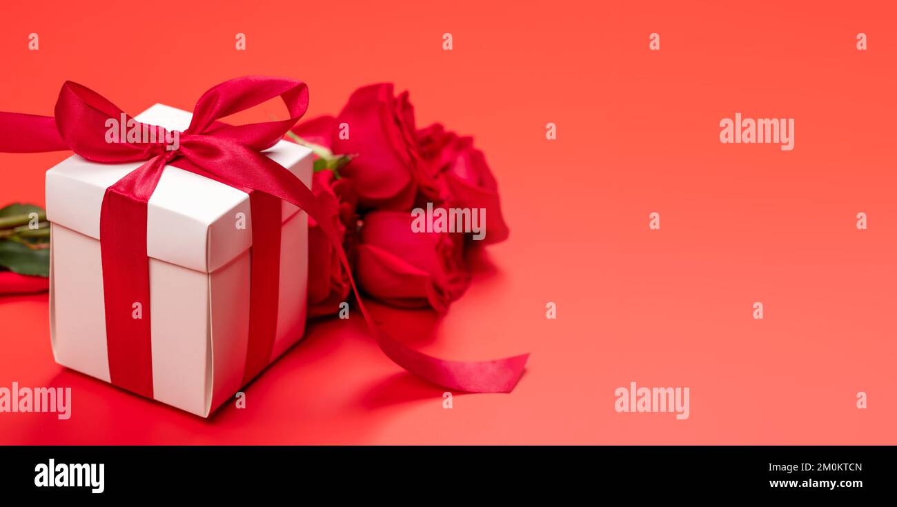 Valentines day card with gift box and rose flowers. On red background ...