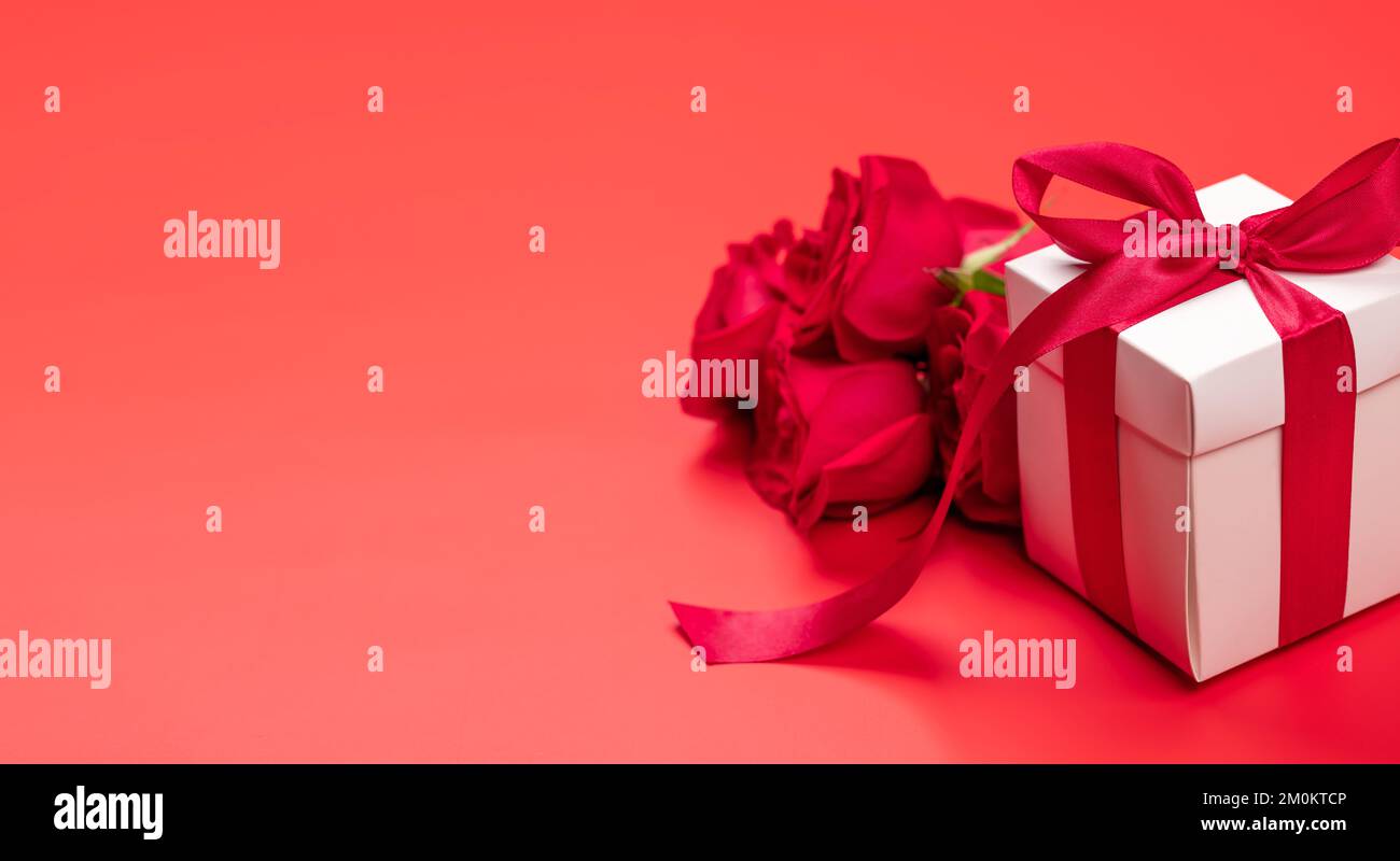 Valentines day card with gift box and rose flowers. On red background ...