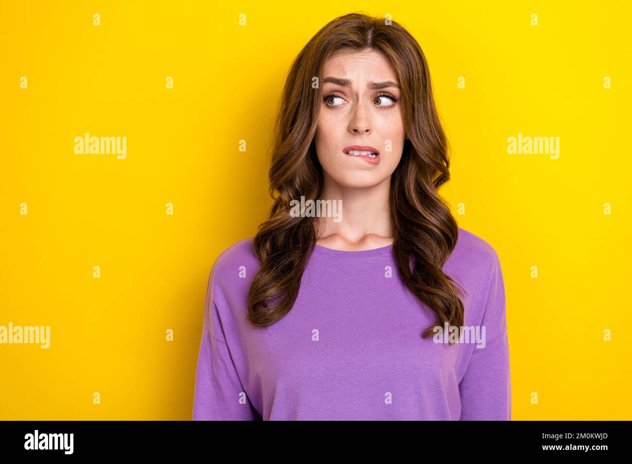 Photo of young nervous cute brown wavy hair woman bite lips looking empty space dont know fix electrics isolated on yellow color background Stock Photo