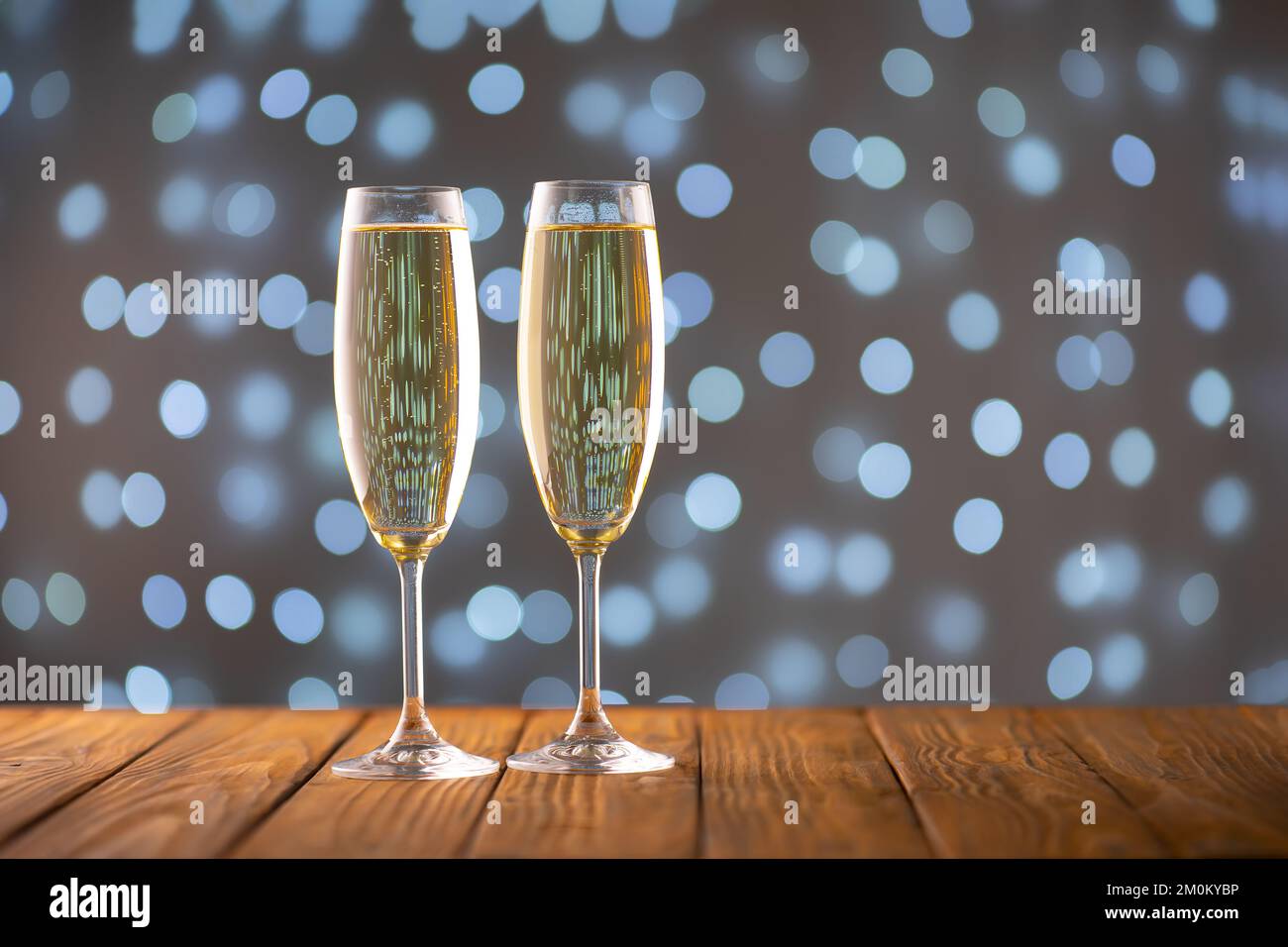 Two wine glasses with bubbly champagne on background of blurry sparkling lights. Happy New Year holiday greeting card, banner, header with copy space Stock Photo
