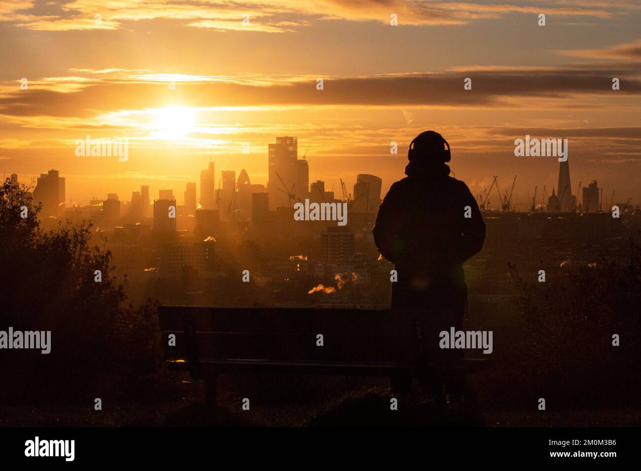 London ,United Kingdom  -06/12/2022. A person looks out across London as the sun rises from Hampstead Heath’s  Parliament Hill as the weather Stock Photo