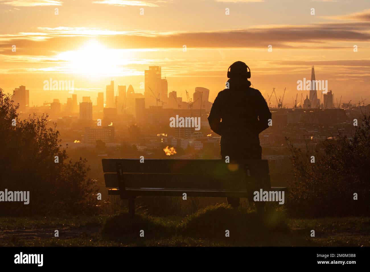 London ,United Kingdom  -06/12/2022. A person looks out across London as the sun rises from Hampstead Heath’s  Parliament Hill as the weather Stock Photo