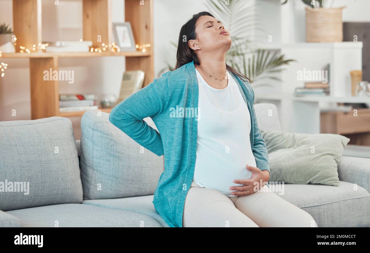 Pregnant woman, breathing and stomach pain on sofa in living room for