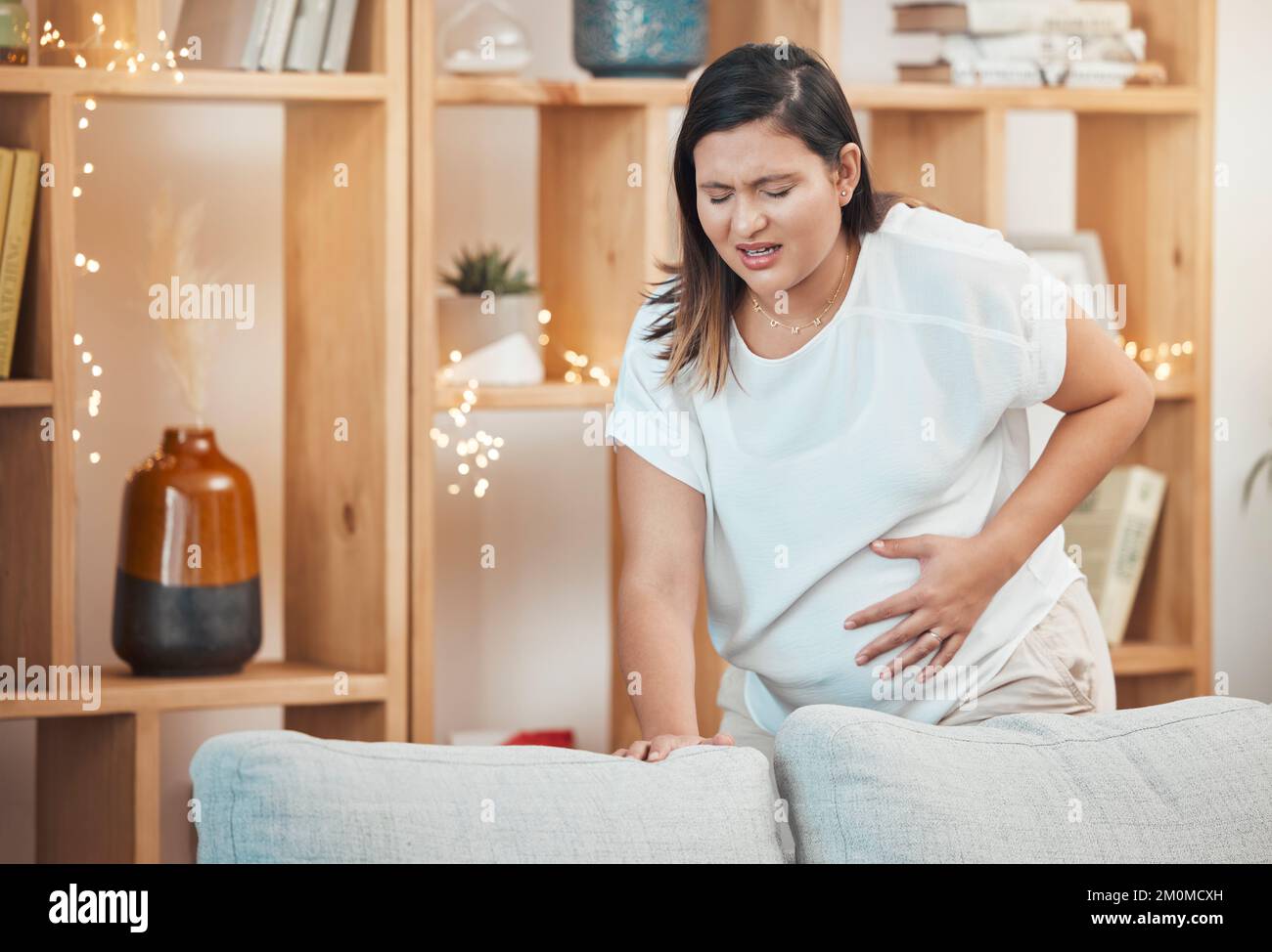 Pregnant woman, pain and cramps with hand on stomach for abdominal problem, discomfort or childbirth contractions for labour. Female with stress Stock Photo