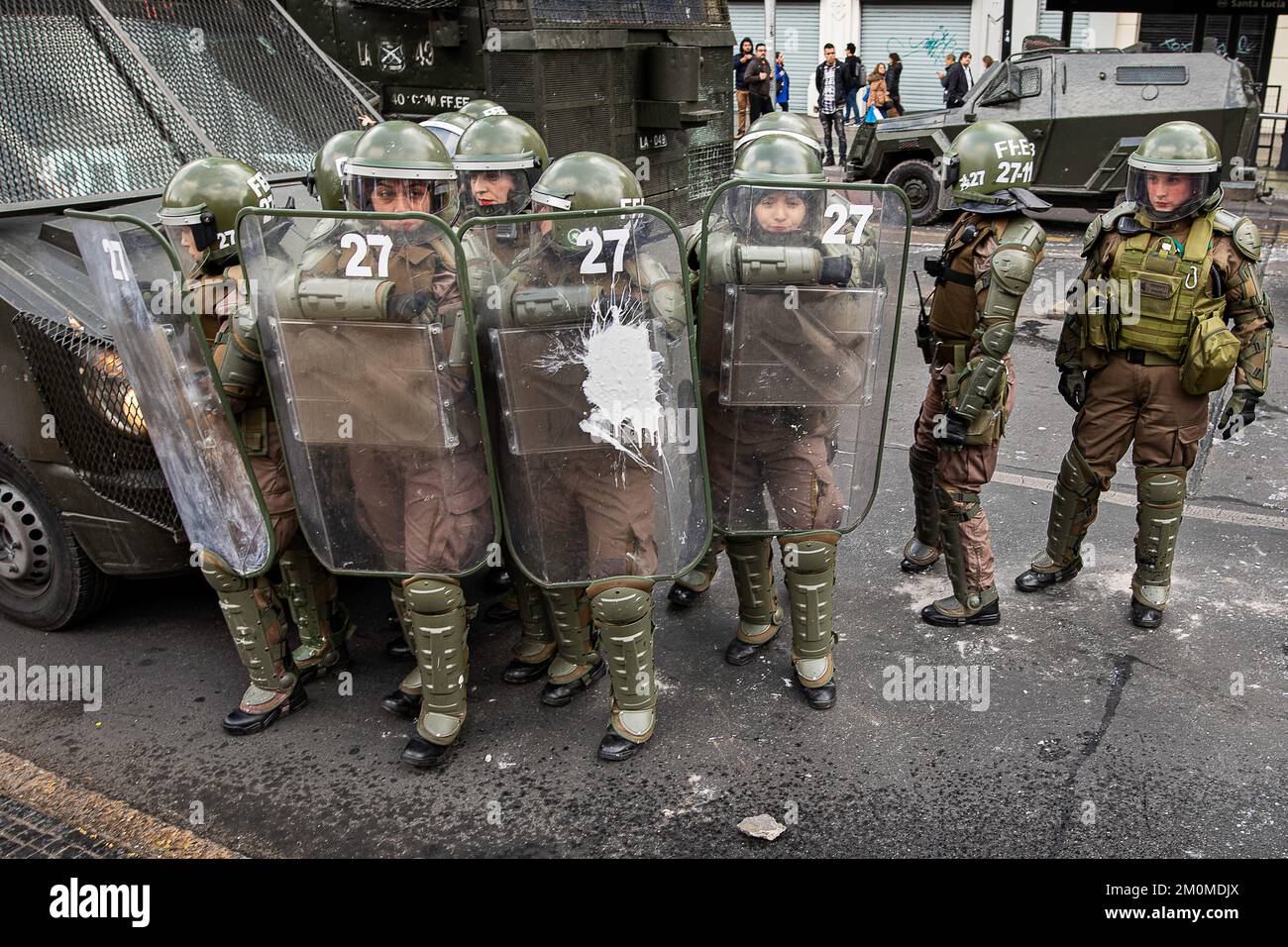 Female riot police officers at a student demonstration on Avenida Libertador Bernardo O'Higgins. One of the officers received a ballon of white paint. Stock Photo