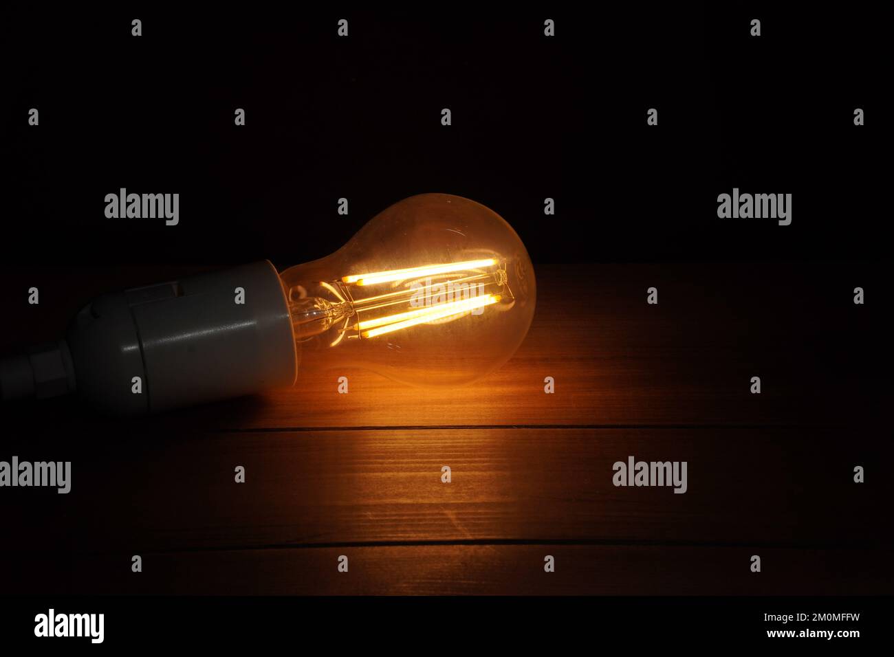 burning light bulb on wood surface and black background Stock Photo