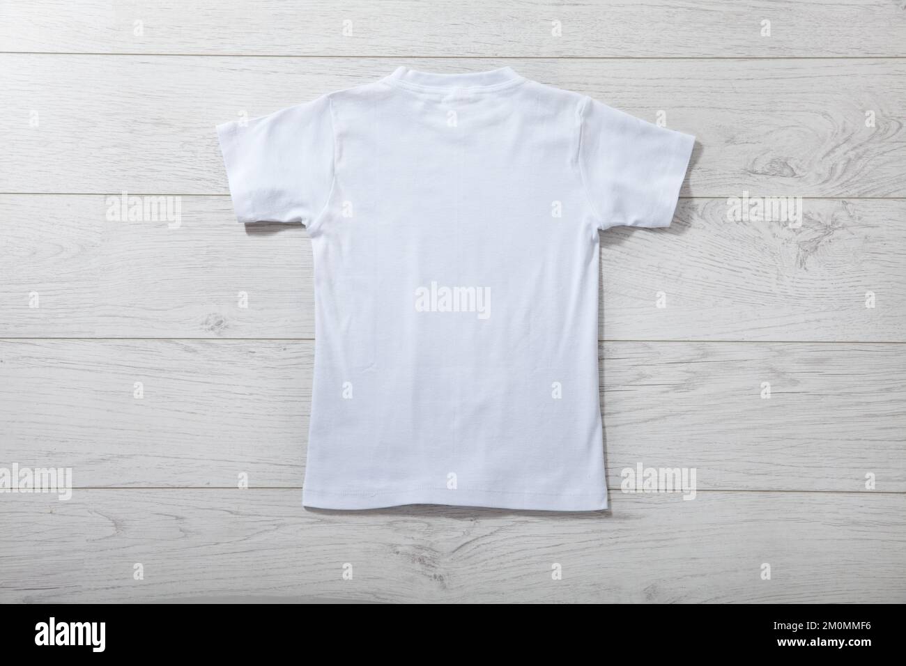 Back views on boys t-shirts on white wooden desk background. Mockup for design close up Stock Photo