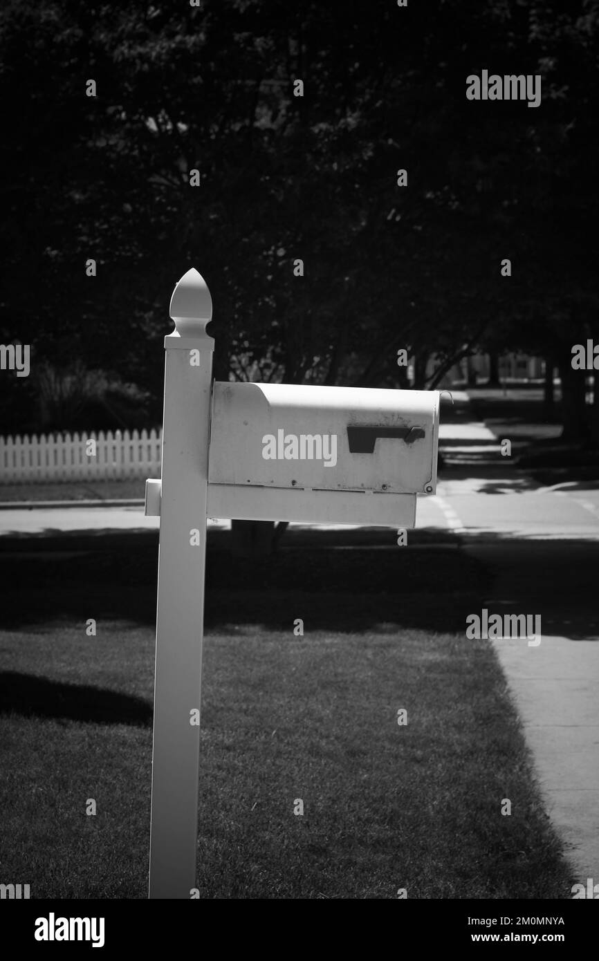 Traditional wooden mailbox post standing near the street in a black and