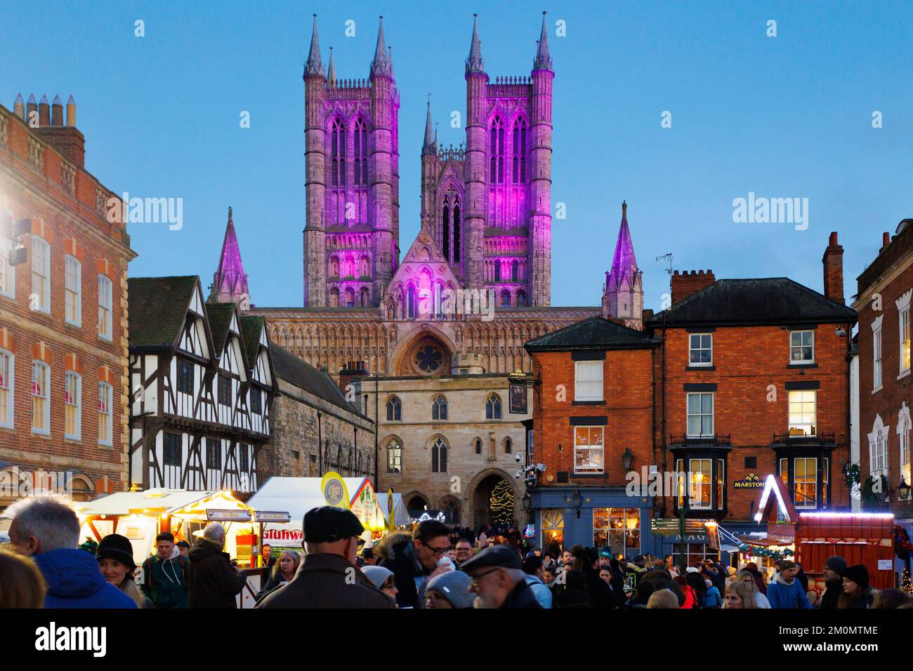 The annual Lincoln Christmas Market held every first weekend in December. The market is held in the uphill area of the City known as Bailgate, mainly around the Cathedral and the Castle. The cathedral if floodlit, in 2022 a blue/purple colour making it a centre piece seen acroos the City. Attracting thousands of people from all over Europe the market at times becomes a one way system to allow the large numbers of people to go around safely. Crowds infront of the floodlit Cathedral. Stock Photo