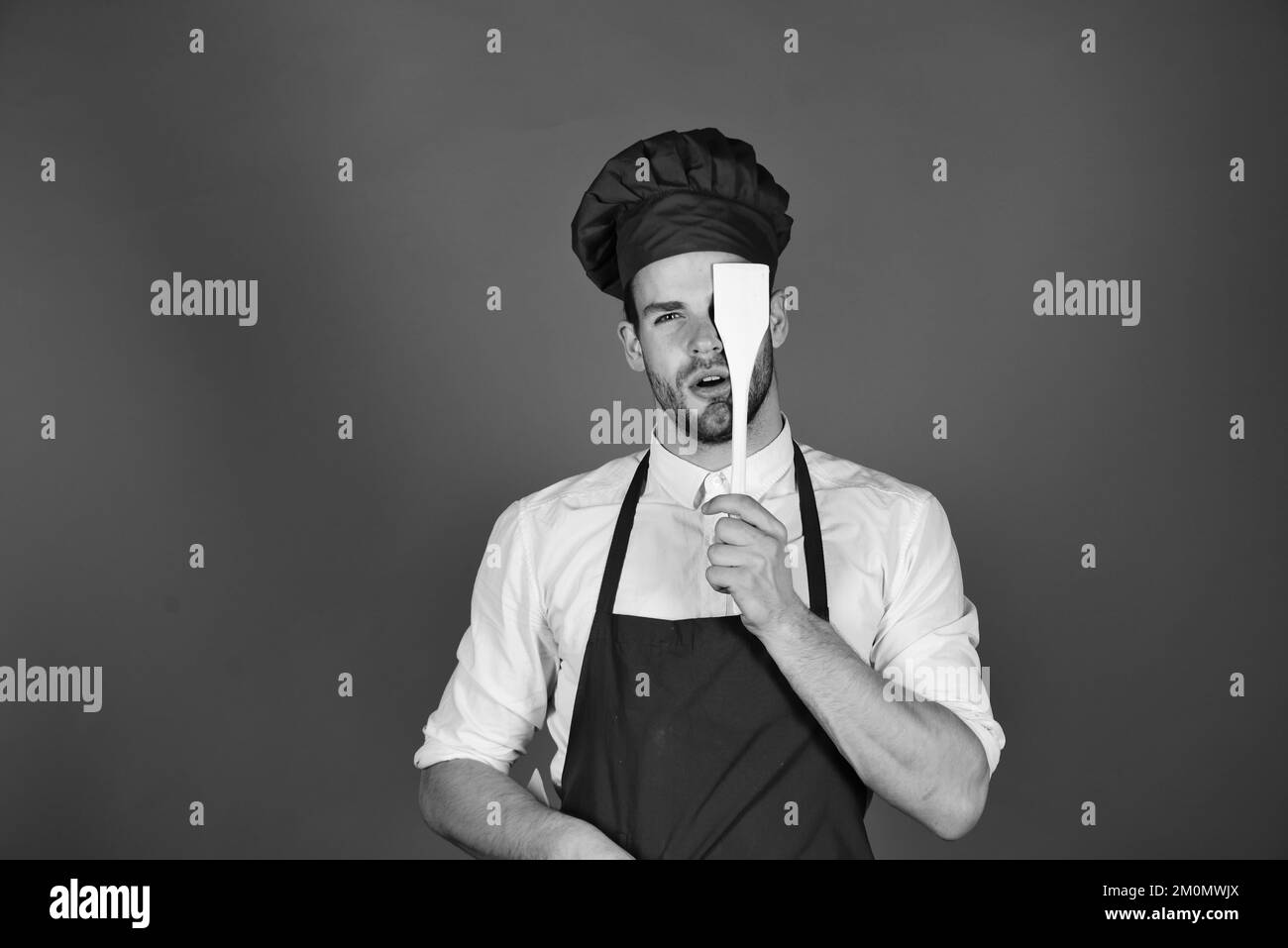 Cook works in kitchen with wooden spatula Stock Photo Alamy