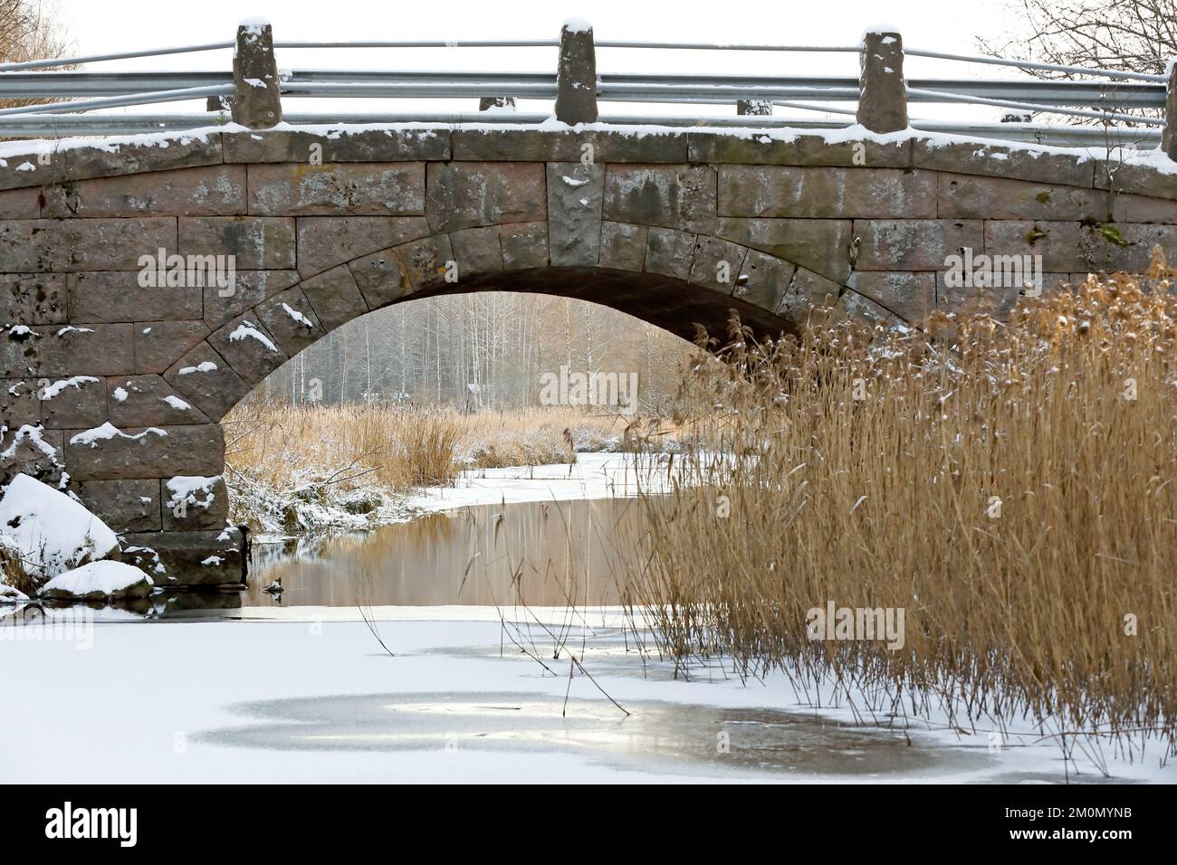 An old stony bridge over narrow freezing river Stock Photo