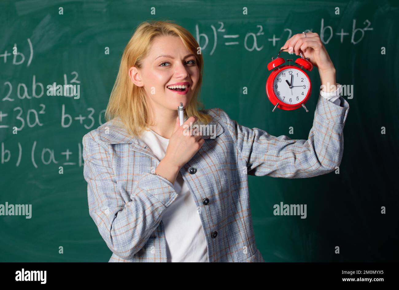 What time is it. Woman teacher hold alarm clock. Girl formal wear