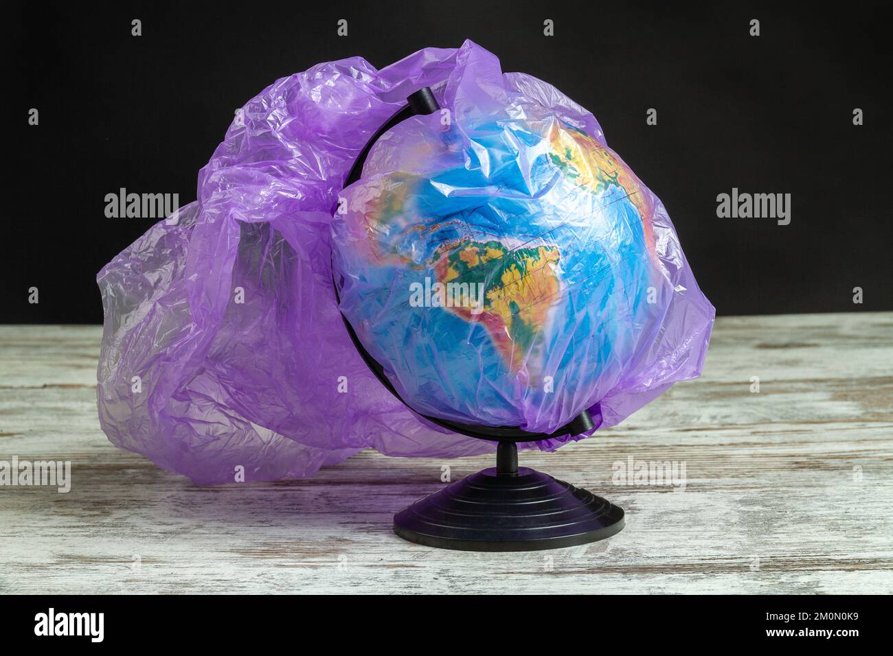 Earth globe covered with purple plastic bag. Concept enviroment pollution. Stock Photo