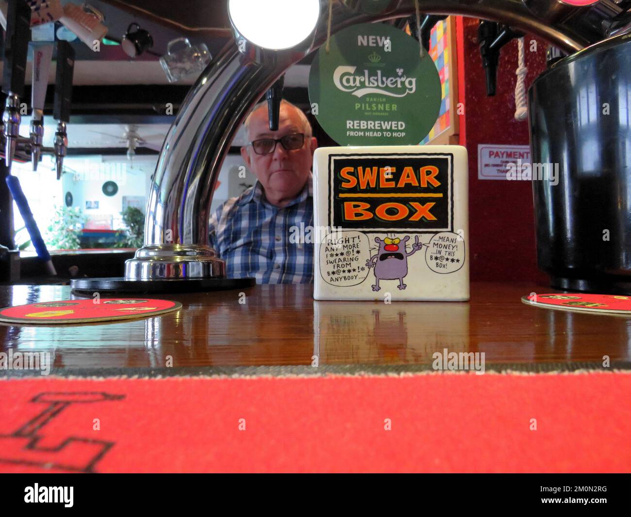 a collection swear box at the bar of a UK pub with a defocused person in the background. Stock Photo