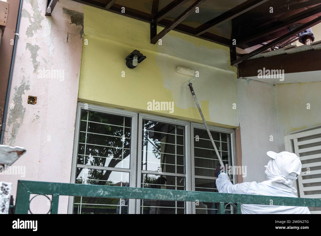 Painter worker adding undercoat foundation paint onto wall with roller