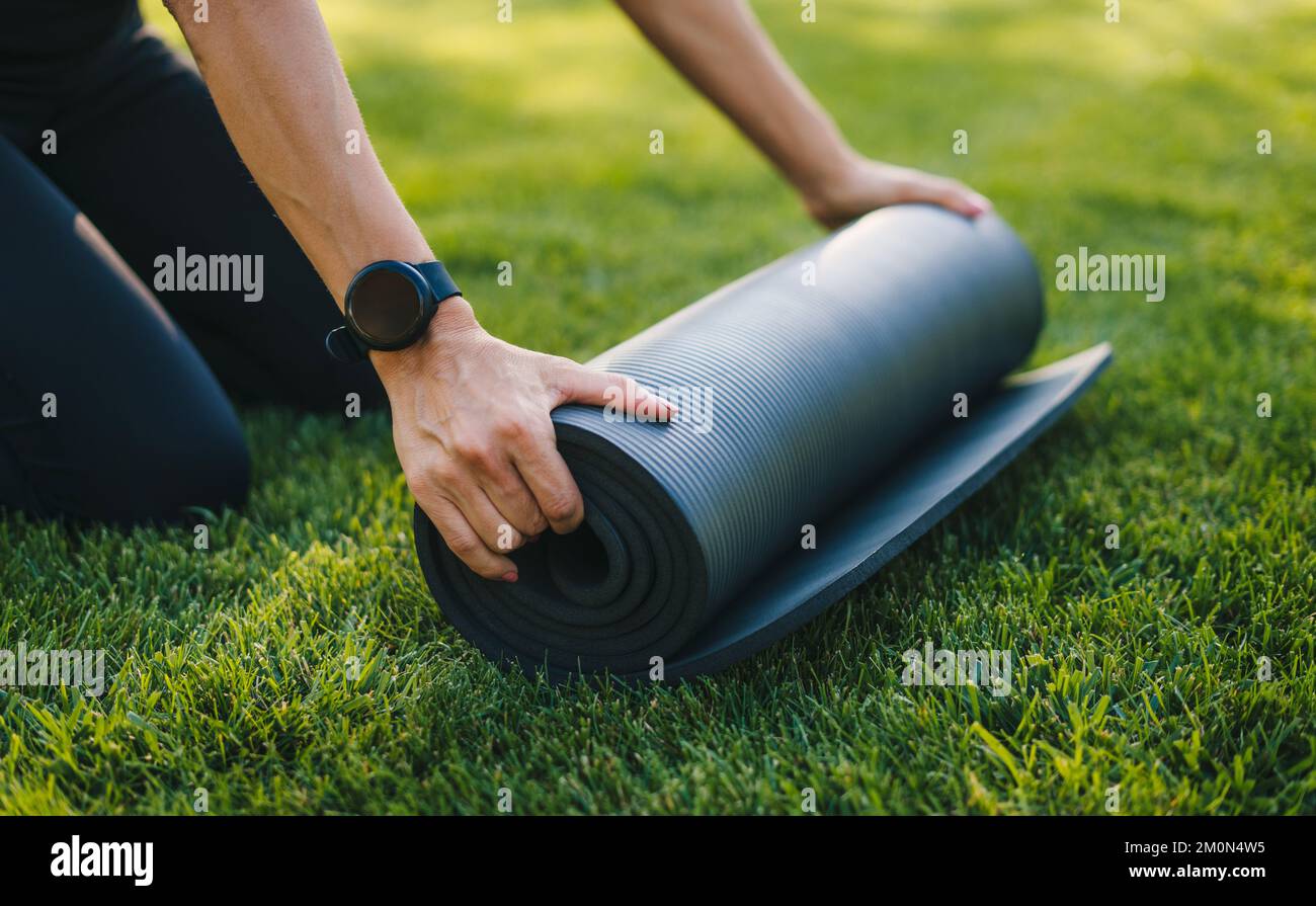 Woman's hands rolling blak yoga ma prepare to exercise in park. Healthy lifestyle, sport. People body fit healthy. Healthy activity. Training workout Stock Photo